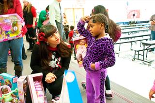 Leslie Valdes, owner of Abuela's Tacos, volunteers handing out toys to students at Kermit Booker Elementary School during the 